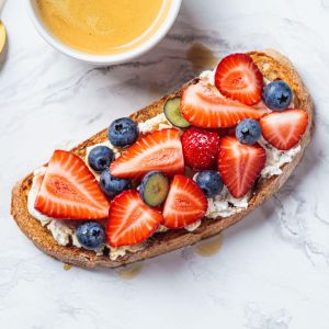 Sliced strawberries, blueberries and ricotta on wholemeal toast