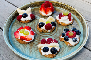 A plate of oaty biscuits decorated with fruit and yoghurt