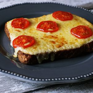Grilled cheese and slices of tomato on top of a slice of wholegrain toast