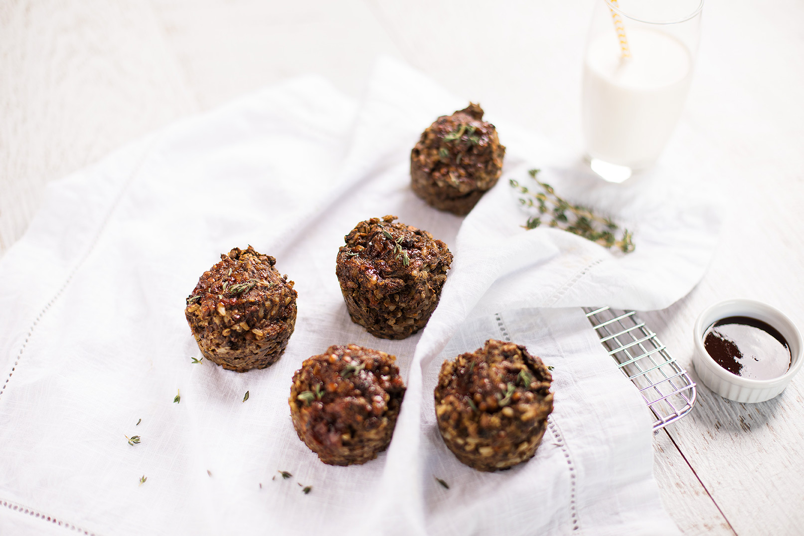Image of five baked lentil and vegetable load cups on a baking paper cooling on a wire cooling rack with a glass of milk in the background