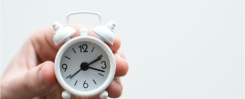 A hand holds an alarm clock
