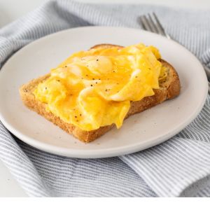 Scrambled egg on wholegrain toast sitting on a white plate