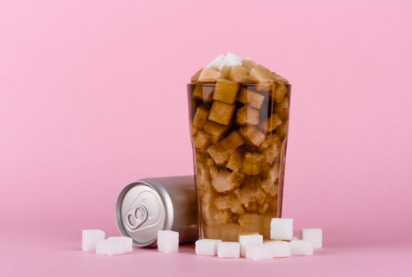 An unlabelled can next to a tall glass of brown liquid filled with sugar cubes