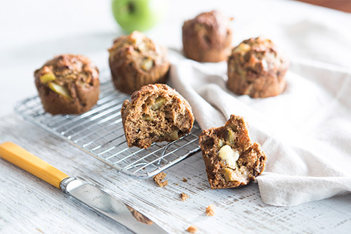 Baked muffins on a try with margarine melting on one and a knife