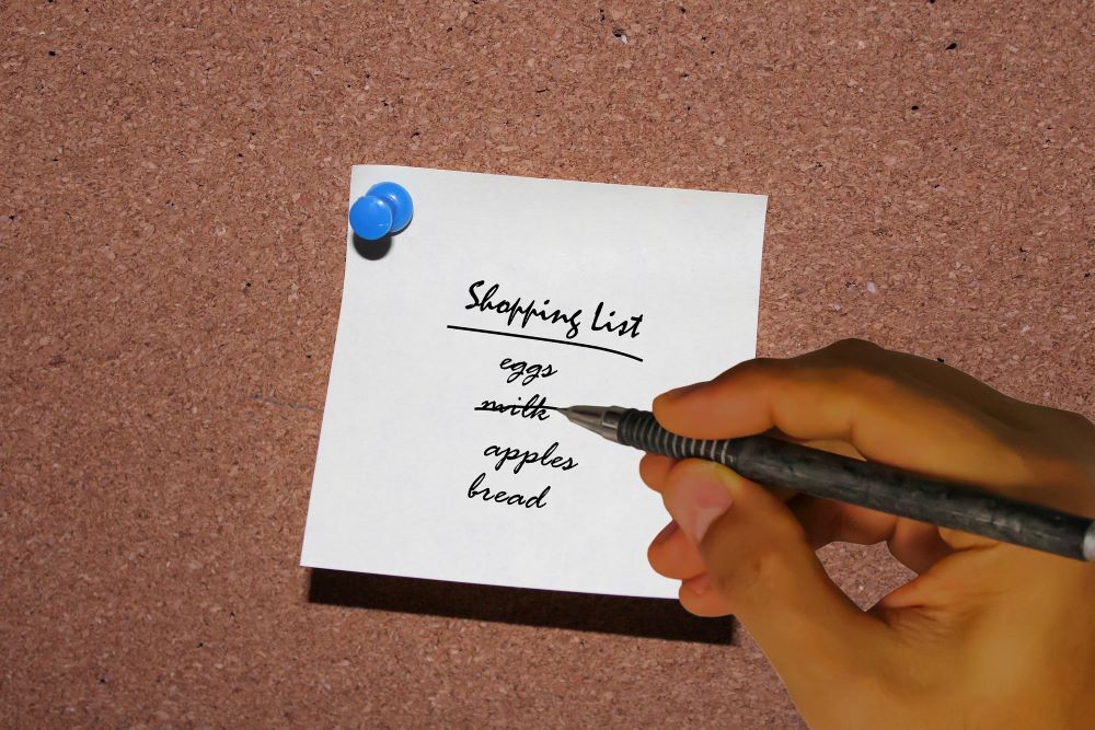 Hand writing a shopping list with a black pen